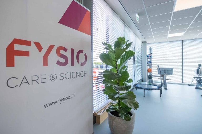 Interieur van Fysio Care & Science praktijk met banner en oefenapparatuur.
